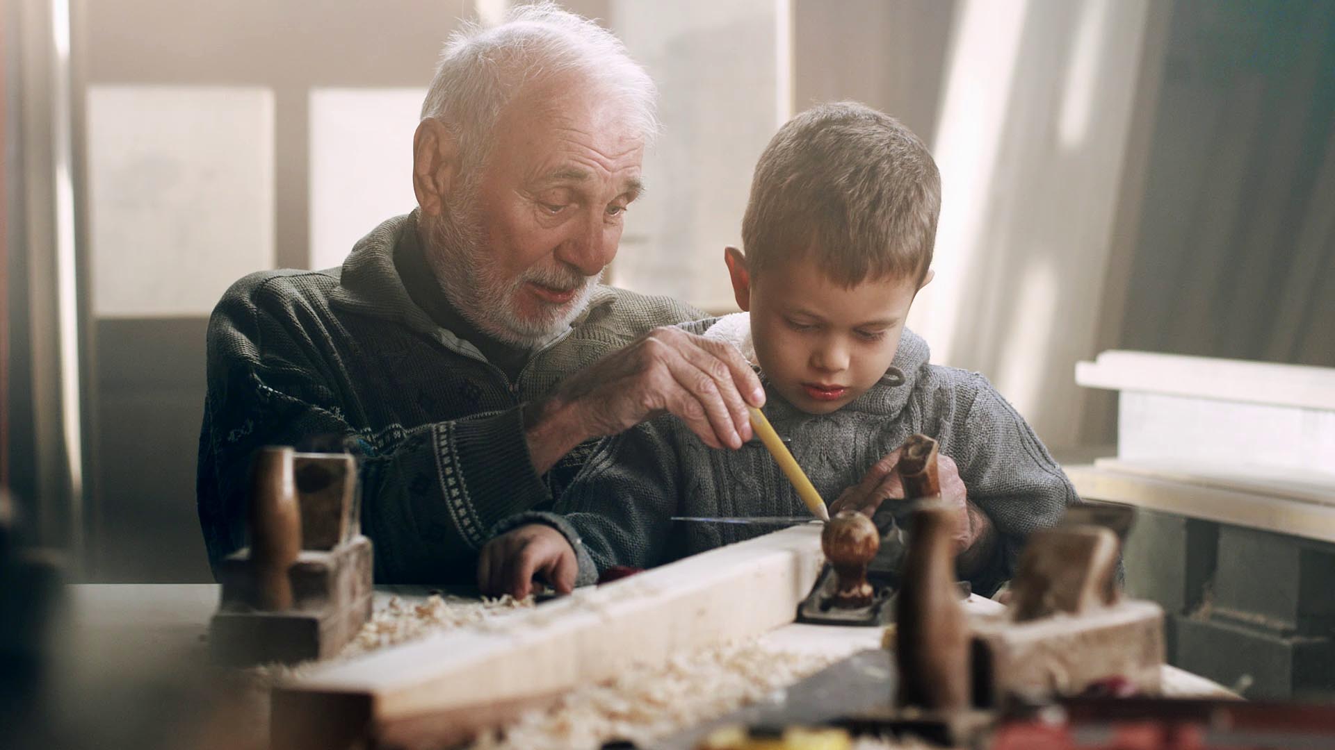 Alter mann zeigt Kind Holzarbeiten